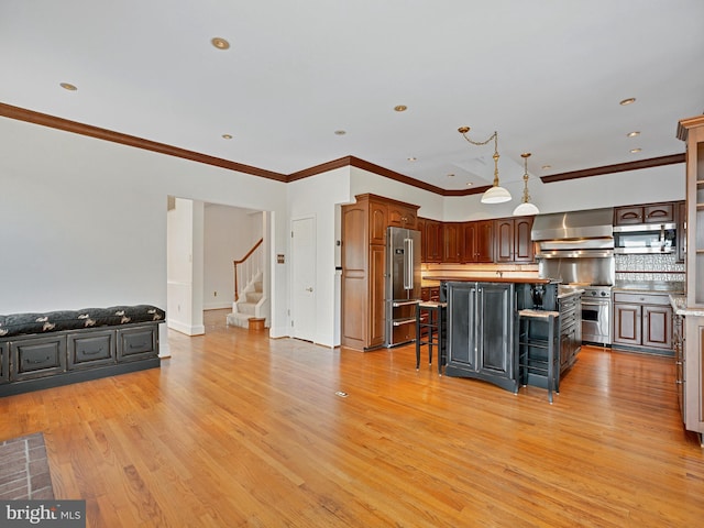 kitchen with high quality appliances, light wood-style flooring, a kitchen bar, wall chimney exhaust hood, and backsplash