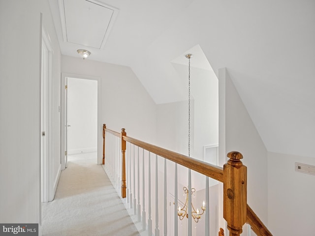 hallway featuring an upstairs landing, attic access, light carpet, and vaulted ceiling