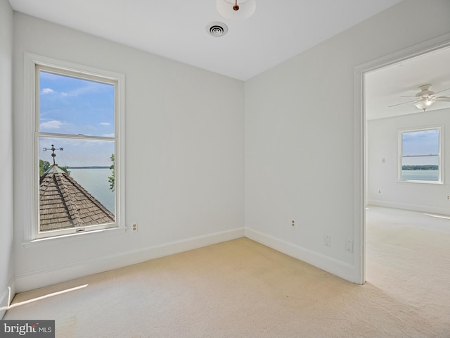 carpeted empty room with a ceiling fan, baseboards, and visible vents