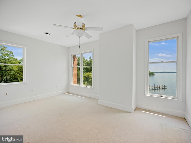 empty room featuring visible vents, baseboards, light colored carpet, and a ceiling fan