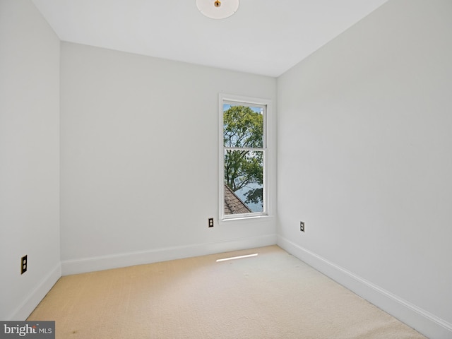 spare room with baseboards and light colored carpet