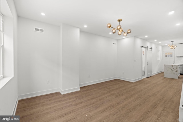 interior space with recessed lighting, visible vents, a barn door, wood finished floors, and a chandelier