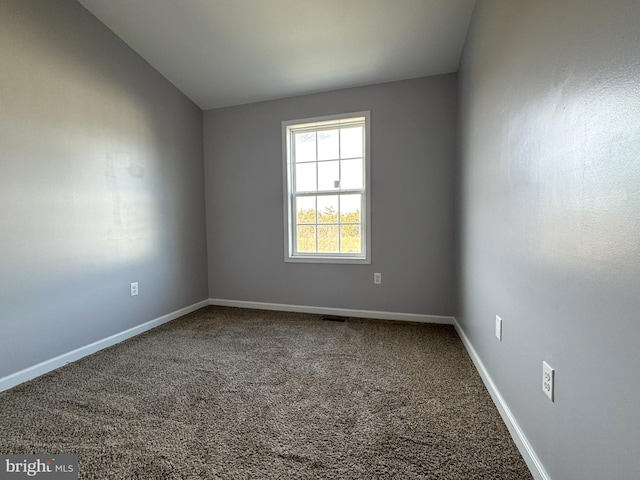 carpeted empty room with lofted ceiling, visible vents, and baseboards