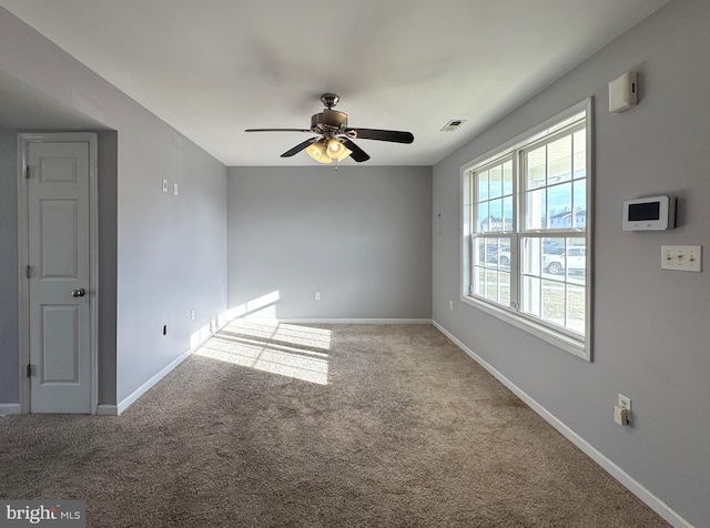 empty room with carpet, visible vents, ceiling fan, and baseboards