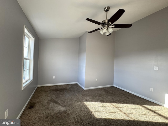 carpeted empty room featuring a ceiling fan, visible vents, and baseboards