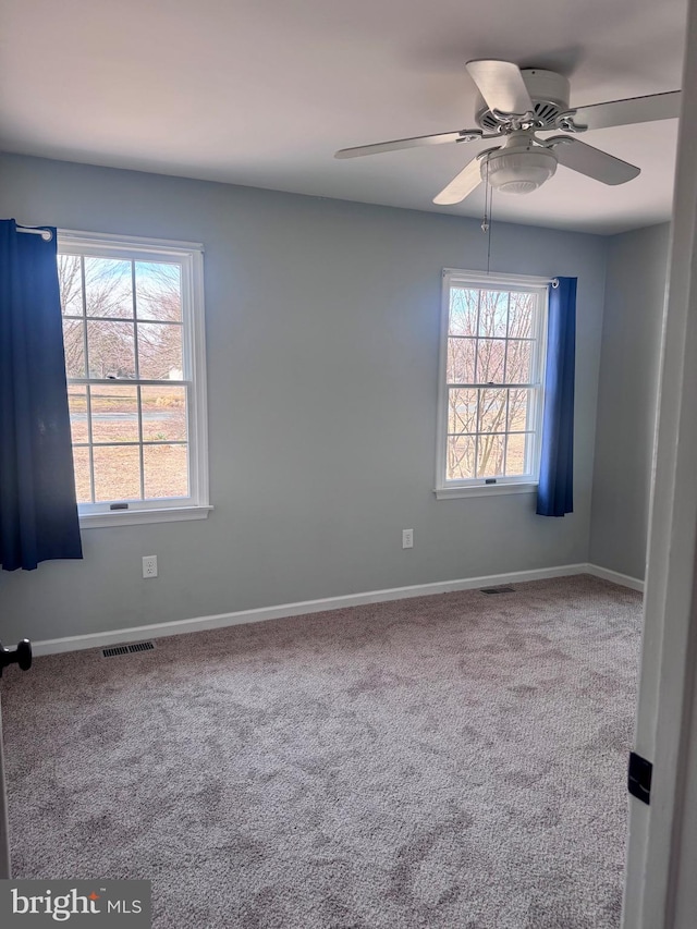 spare room featuring visible vents, plenty of natural light, and carpet floors