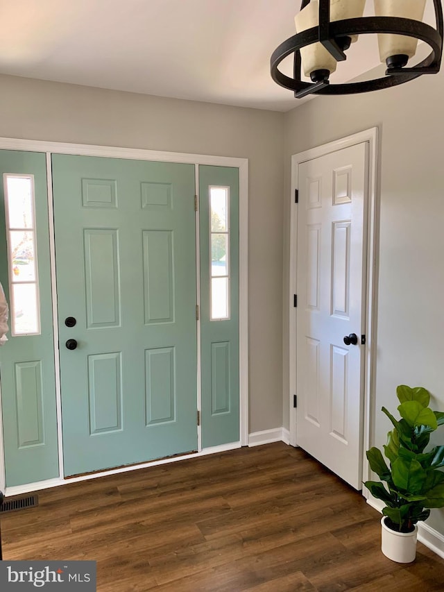 foyer entrance with dark wood finished floors, baseboards, and visible vents