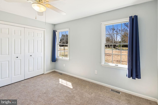 unfurnished bedroom with a closet, carpet flooring, baseboards, and visible vents