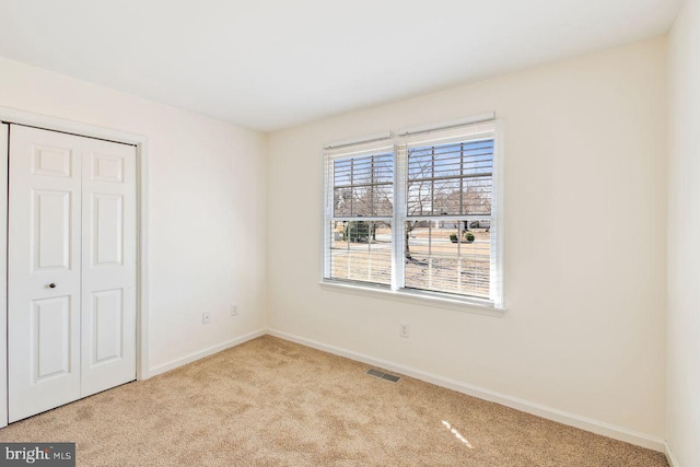 unfurnished bedroom featuring a closet, visible vents, carpet flooring, and baseboards