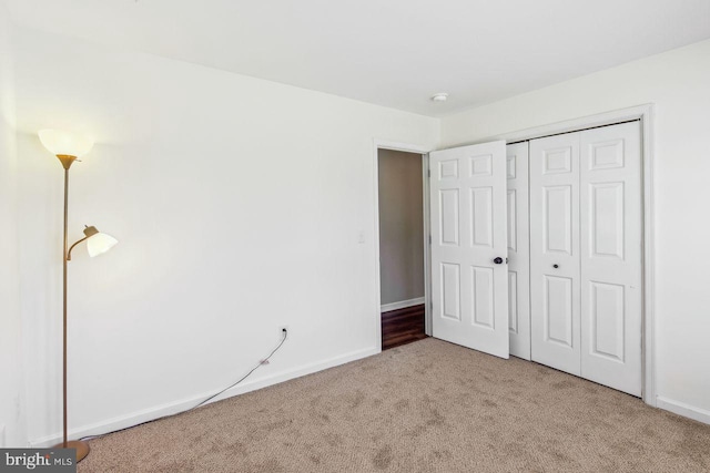 unfurnished bedroom featuring a closet, baseboards, and carpet flooring