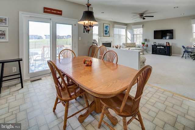 dining space with a fireplace, recessed lighting, visible vents, stone finish floor, and light carpet