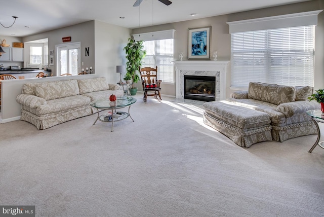 carpeted living area with ceiling fan and a high end fireplace