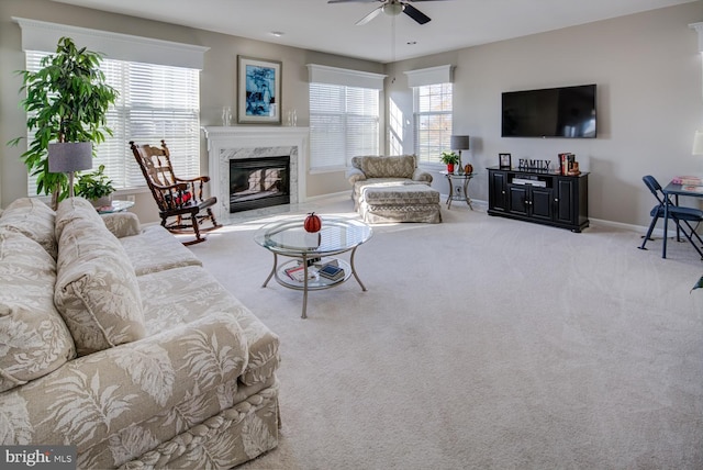 living room with a high end fireplace, baseboards, ceiling fan, and carpet