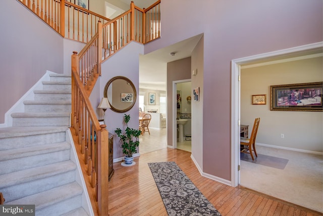 stairs featuring a towering ceiling, baseboards, and hardwood / wood-style flooring