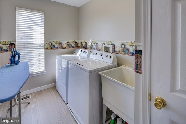 laundry area featuring light tile patterned floors, laundry area, washing machine and clothes dryer, and a wealth of natural light