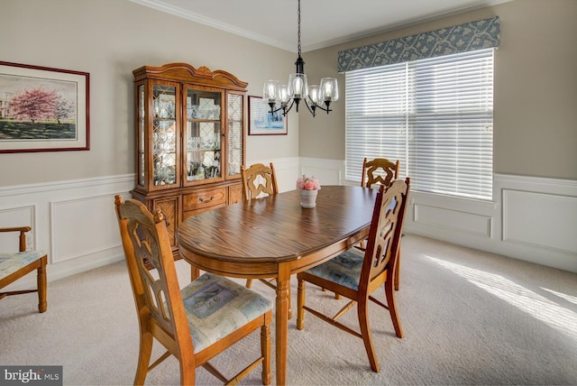 dining area featuring light carpet, a chandelier, and wainscoting