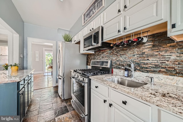 kitchen with backsplash, appliances with stainless steel finishes, white cabinets, and a sink