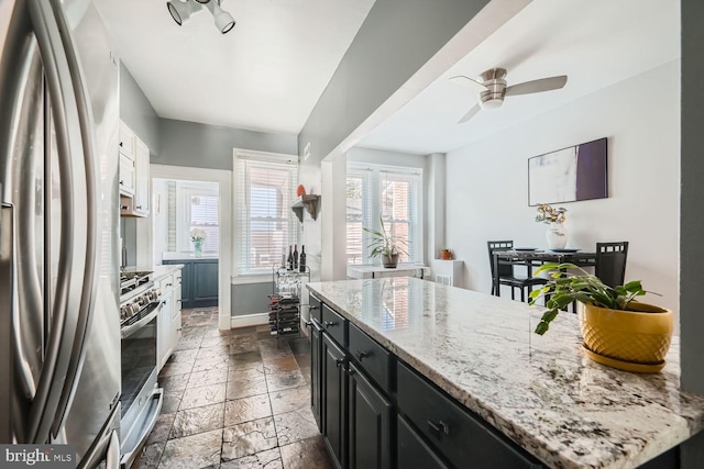 kitchen featuring stone tile floors, white cabinets, a kitchen island, appliances with stainless steel finishes, and dark cabinetry