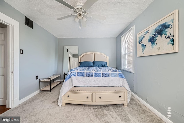 bedroom featuring light carpet, a textured ceiling, visible vents, and baseboards