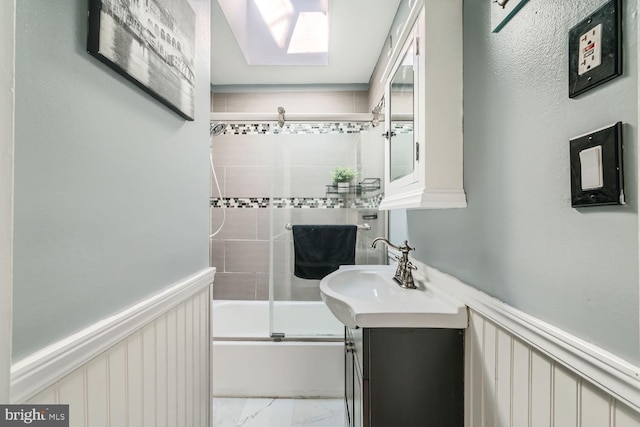 full bathroom featuring enclosed tub / shower combo, marble finish floor, wainscoting, and vanity