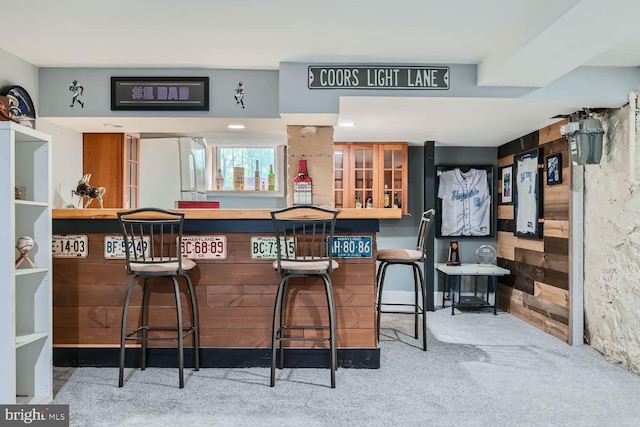 bar with freestanding refrigerator, carpet, wood walls, and a dry bar