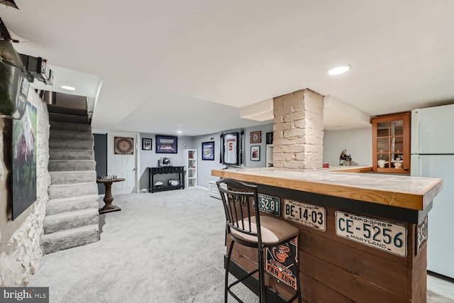 bar featuring light carpet, stairway, freestanding refrigerator, a bar, and ornate columns