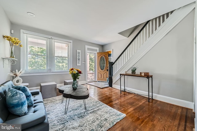 living room featuring stairs, hardwood / wood-style flooring, and baseboards