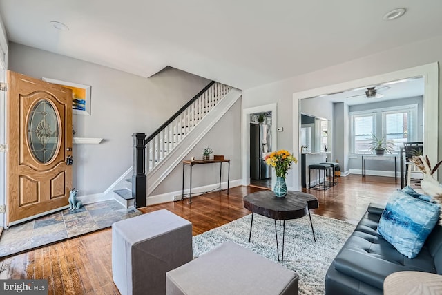 living area with stairs, ceiling fan, wood finished floors, and baseboards