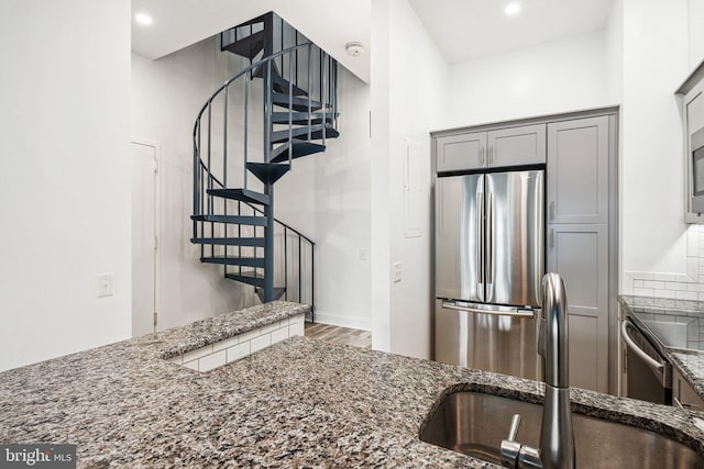 kitchen featuring dark stone counters, wood finished floors, freestanding refrigerator, gray cabinets, and recessed lighting