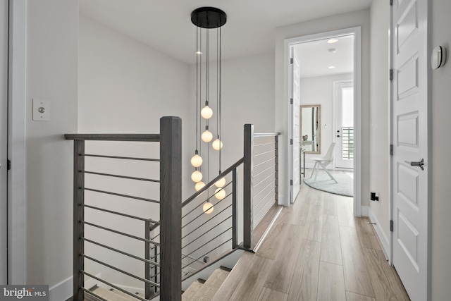 hallway with wood finished floors, an upstairs landing, and baseboards