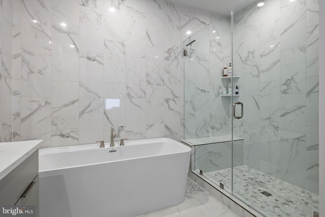 full bathroom with vanity, stone wall, a freestanding bath, a shower stall, and marble finish floor