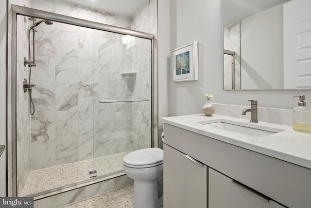 full bathroom featuring a marble finish shower, toilet, and vanity