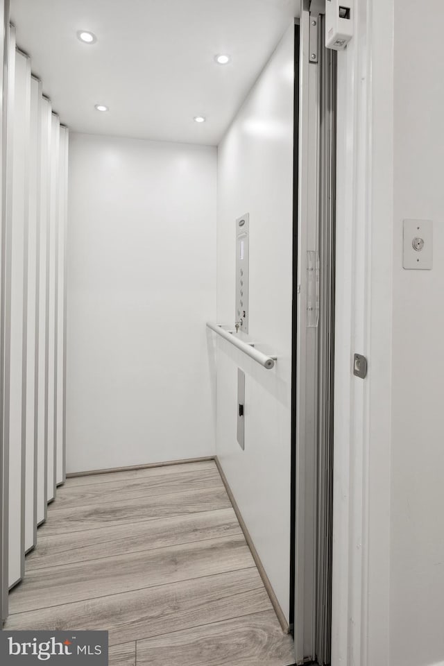 hallway featuring recessed lighting, elevator, and light wood-style flooring