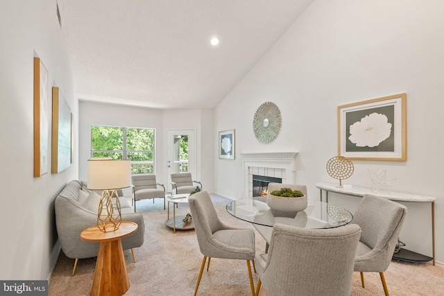 dining area with baseboards, high vaulted ceiling, light colored carpet, recessed lighting, and a tile fireplace