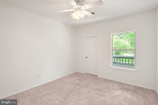 spare room with baseboards, light carpet, a ceiling fan, and visible vents