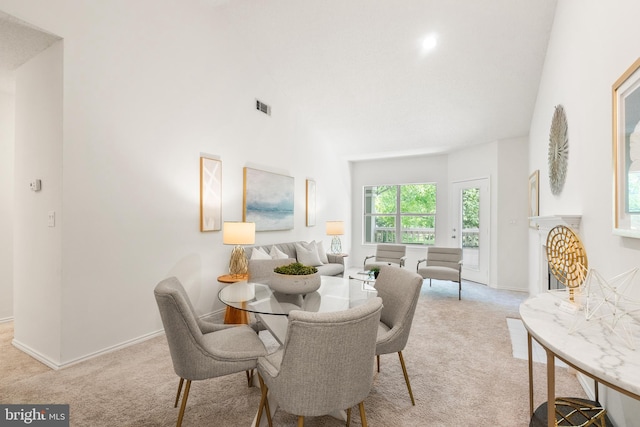 dining area featuring high vaulted ceiling, visible vents, baseboards, and light colored carpet