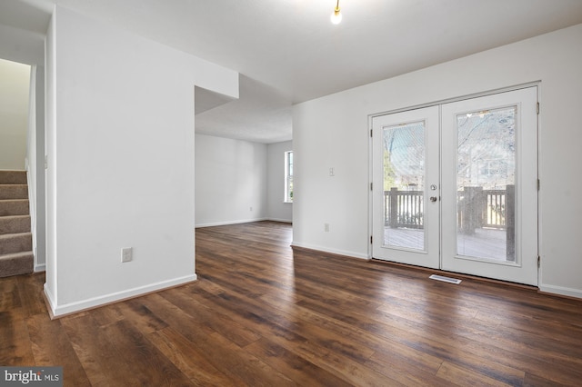 unfurnished room with dark wood-type flooring, visible vents, baseboards, french doors, and stairway