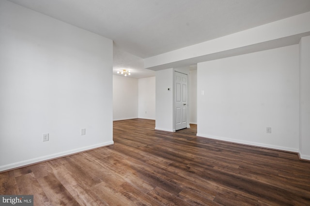 spare room with baseboards and dark wood-style flooring