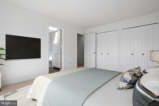 bedroom featuring carpet floors, connected bathroom, baseboards, and two closets