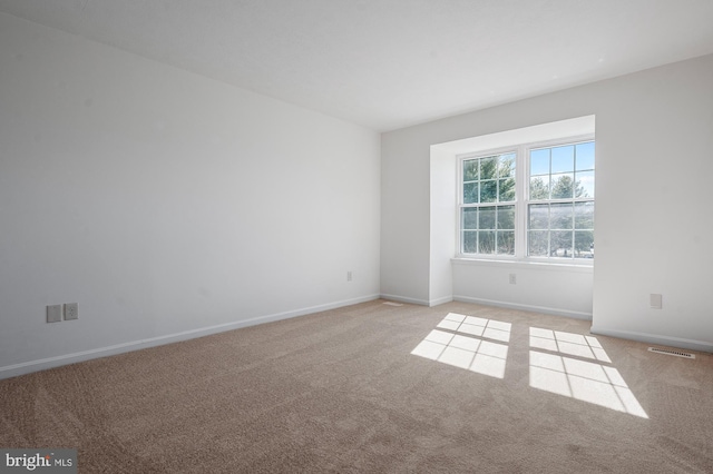 unfurnished room featuring baseboards, visible vents, and light colored carpet