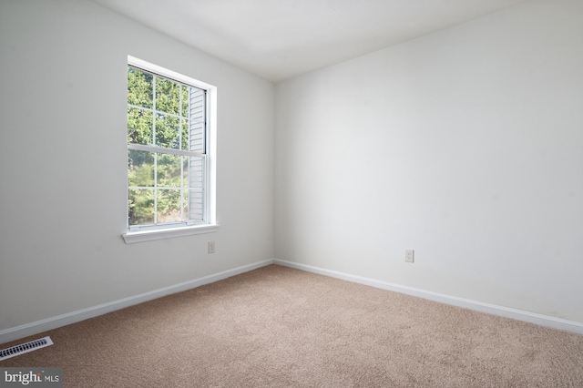 empty room with carpet flooring, visible vents, and baseboards