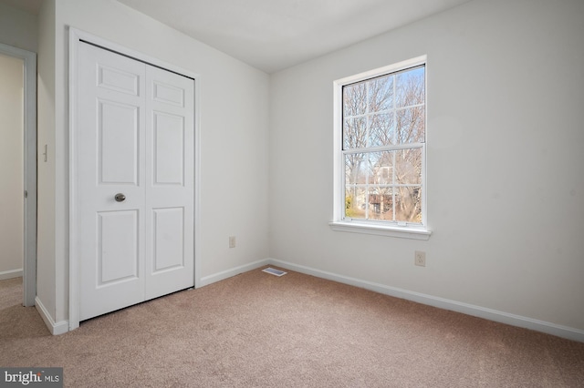 unfurnished bedroom featuring carpet floors, a closet, visible vents, and baseboards