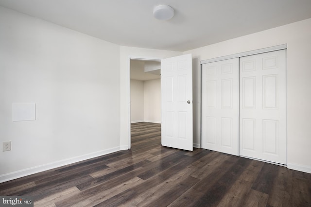 unfurnished bedroom featuring dark wood-style floors, a closet, and baseboards