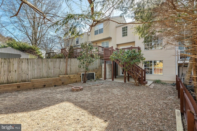 rear view of property with a fire pit, fence, stairway, and a deck