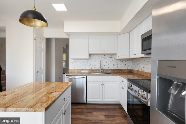 kitchen with dark wood-style floors, pendant lighting, stainless steel appliances, white cabinetry, and a sink