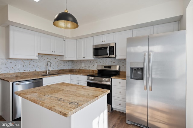 kitchen with white cabinetry, a center island, appliances with stainless steel finishes, and decorative light fixtures