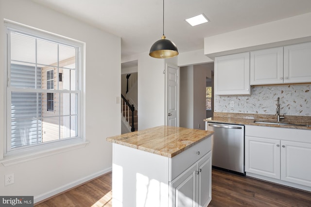 kitchen with white cabinets, hanging light fixtures, light stone countertops, stainless steel dishwasher, and a sink