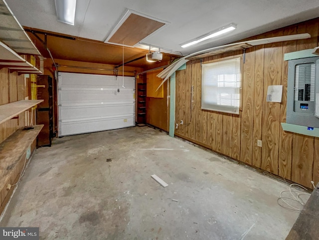 garage featuring a garage door opener, electric panel, and wood walls