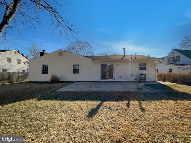 rear view of house with a patio area, a yard, a chimney, and fence