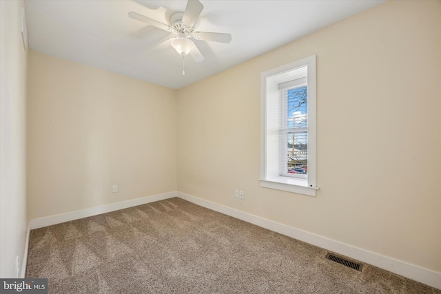 carpeted spare room featuring a ceiling fan, visible vents, and baseboards